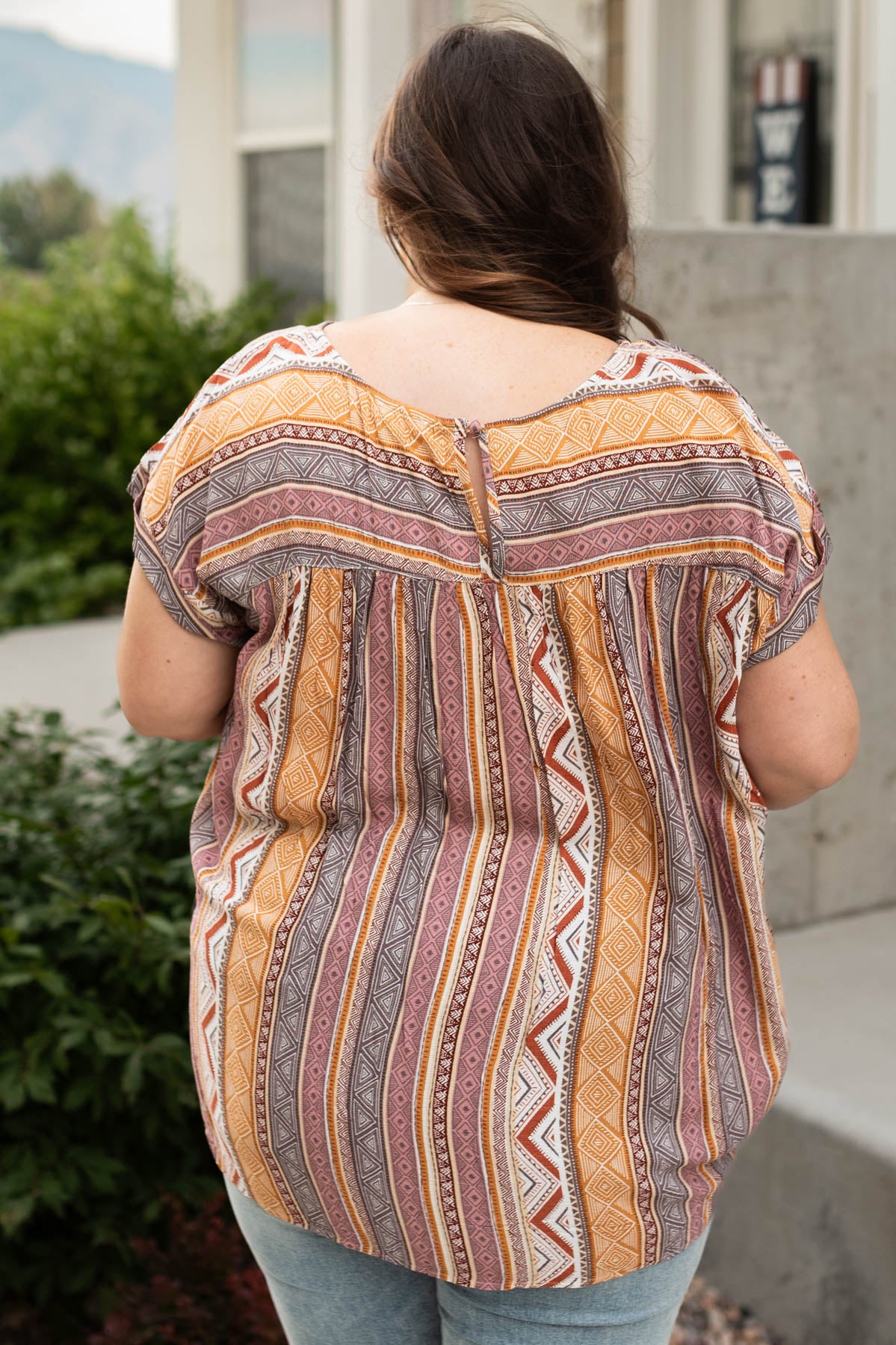 Back view of a plus size multi top with button closer