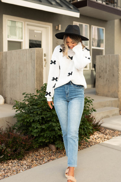 White sweater with long sleeves and black bows