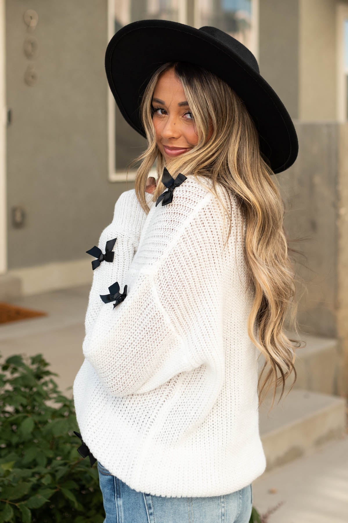 Side view of a white sweater with black bows