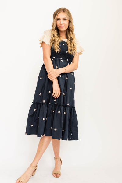 Navy sundress, elastic straps, smocked bodice with white floral print.