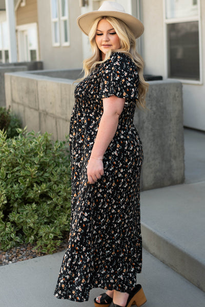 Side view of a plus size black floral dress with short sleeves