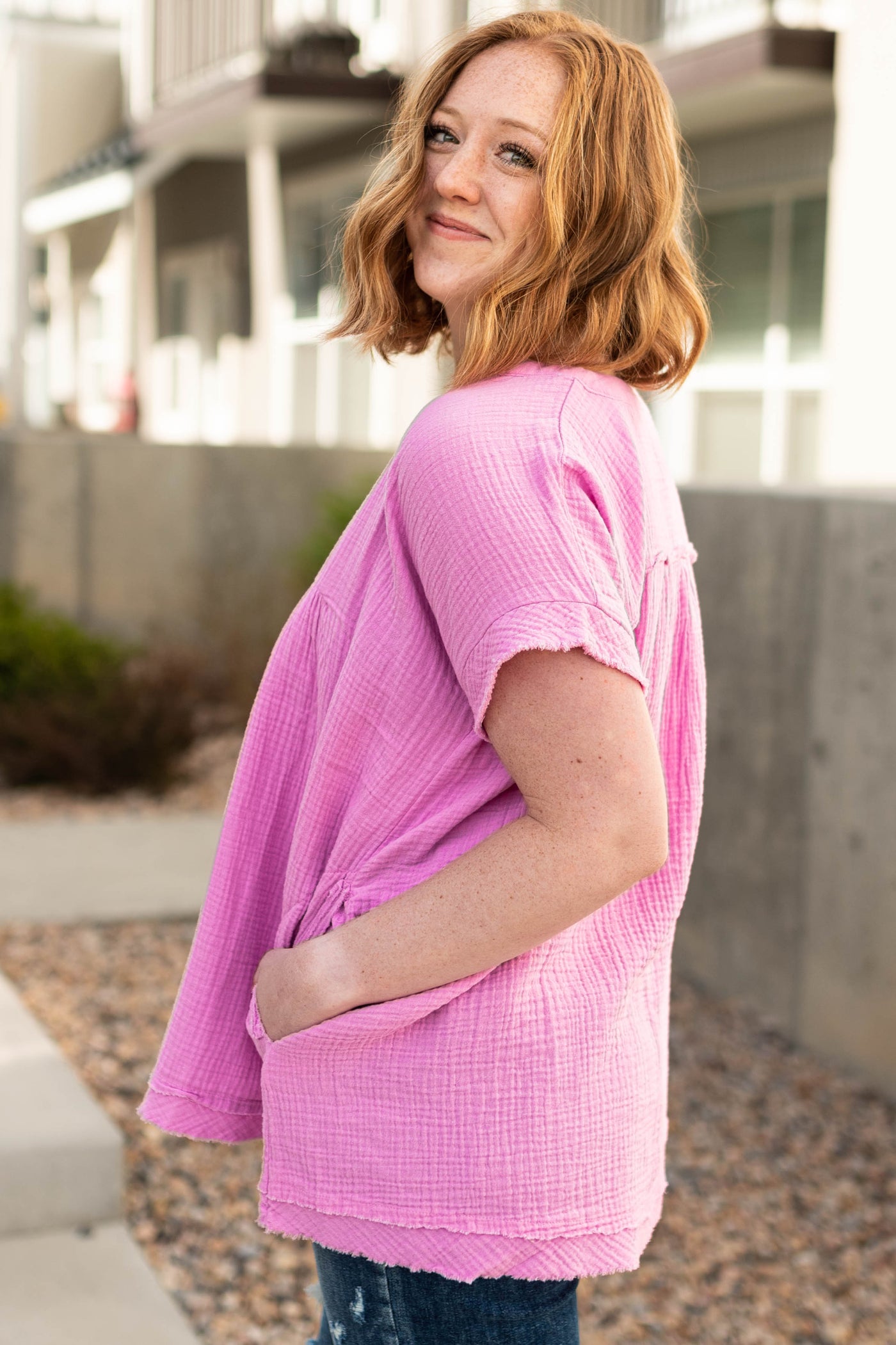 Side view of a mauve short sleeve top with a v-neck and pockets.