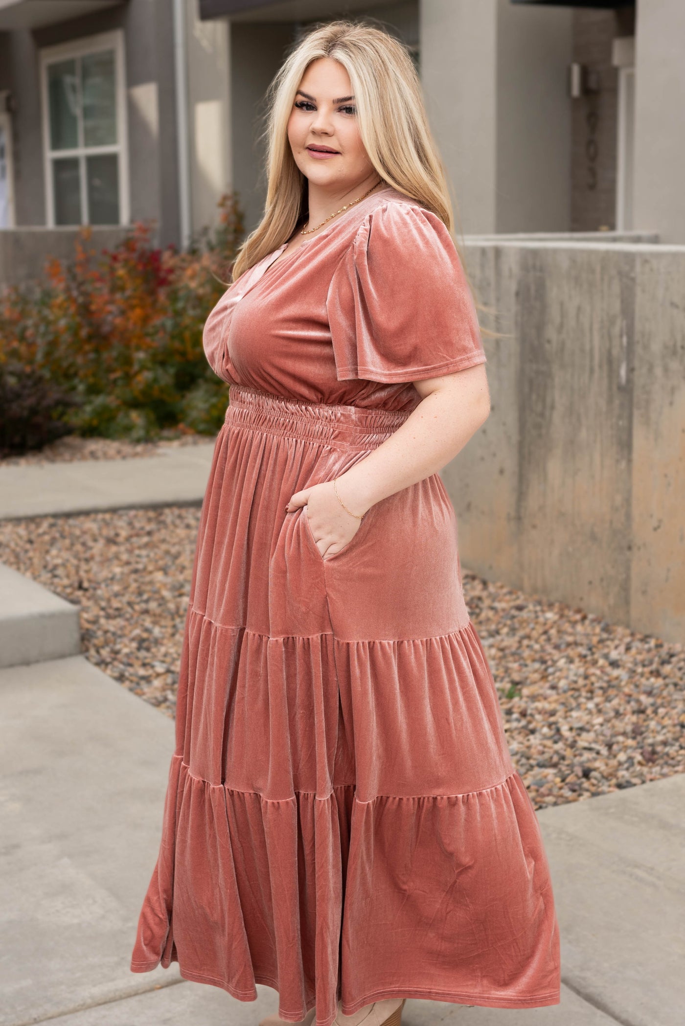Side view of a velvet plus size blush dress with pockets