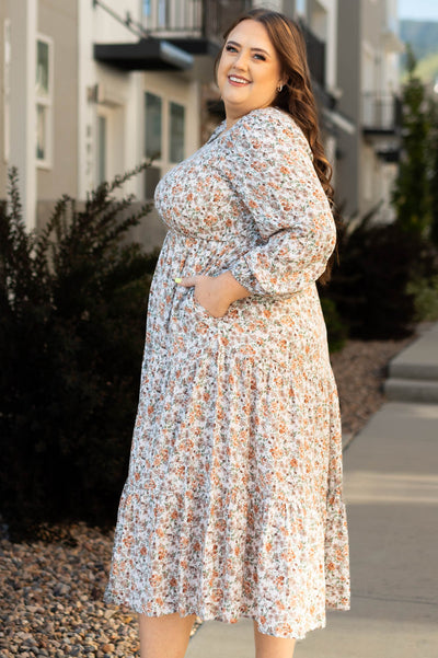 Side view of a plus size taupe floral dress with pockets