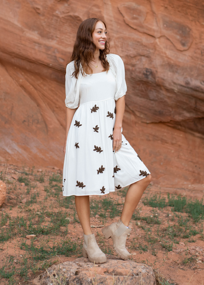 Short sleeve ivory dress with smocked bodice and leaf print on skirt