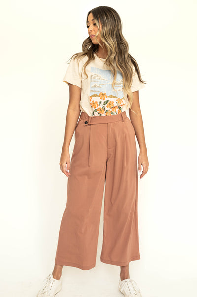Front view of caramel wide leg pleated pants with button at waist.