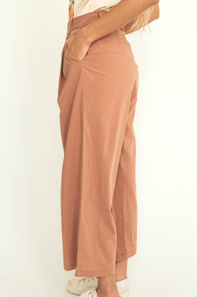 Side view of caramel wide leg pleated pants with button at waist.