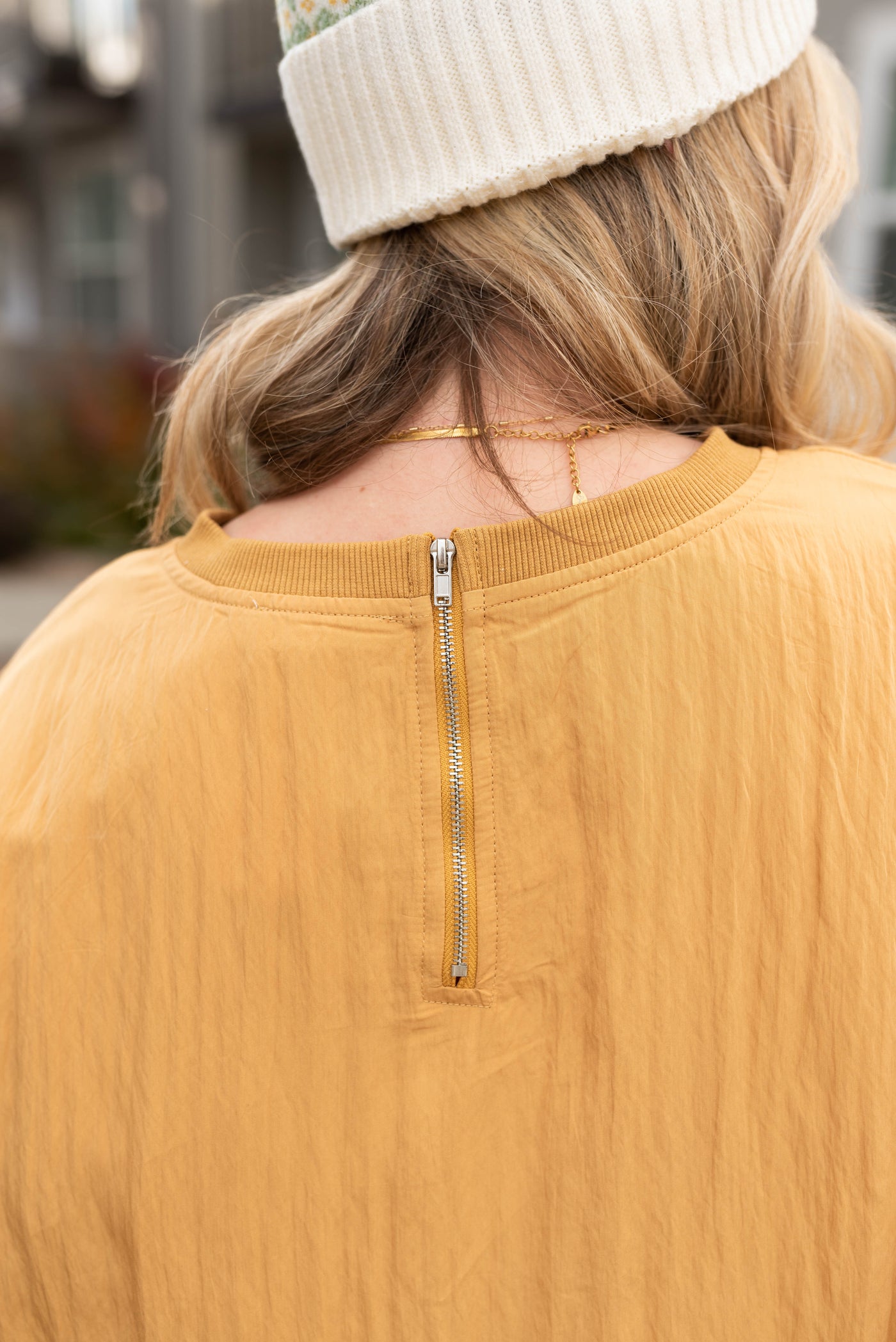 Back view of the mustard parachute blouse with a zipper