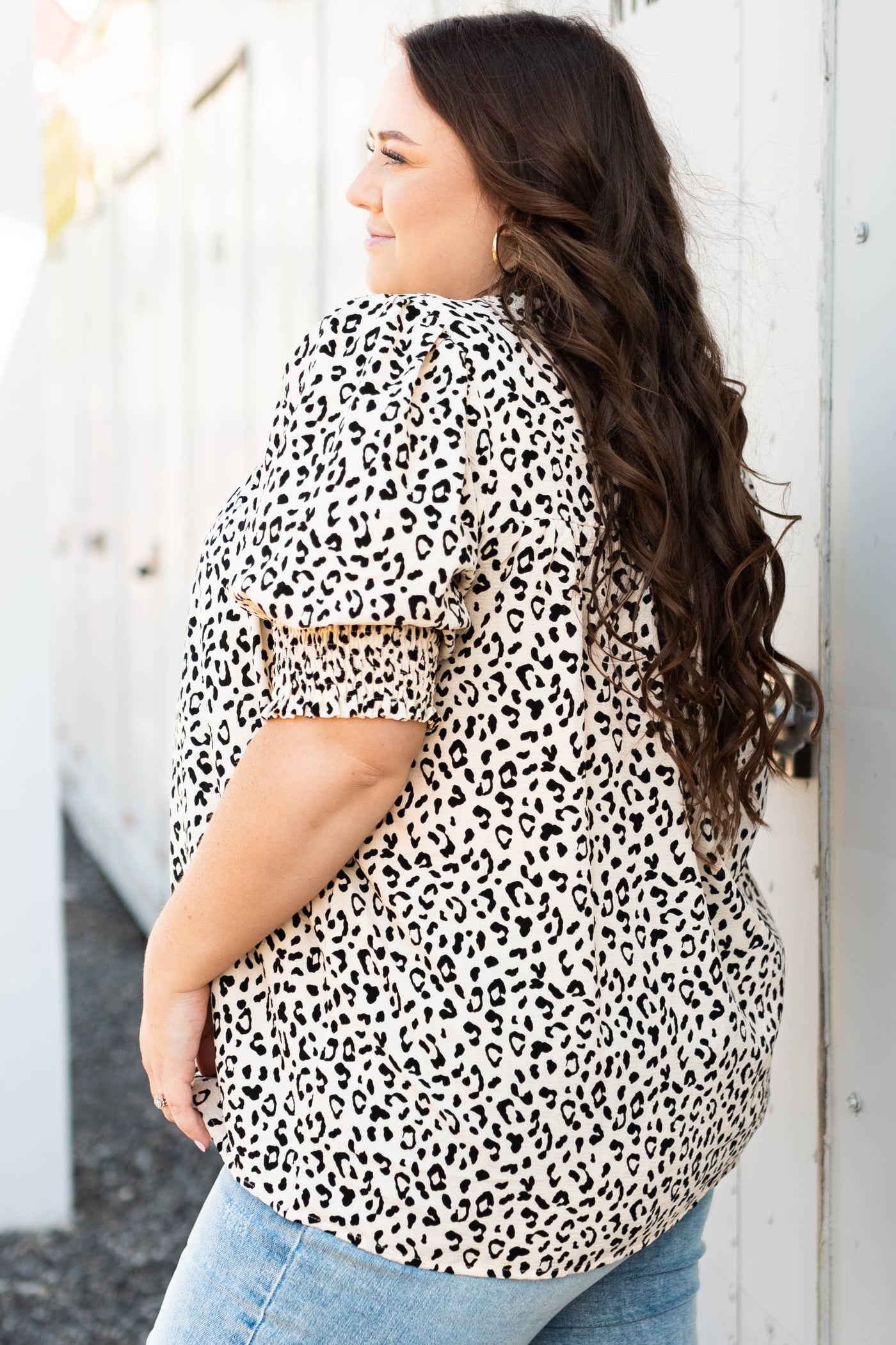 Side view of a plus size cream leopard top with embroidery at the neck