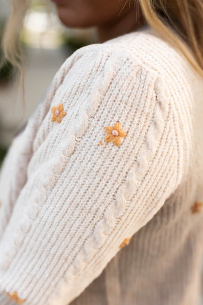 Floral detail of a cream cardigan