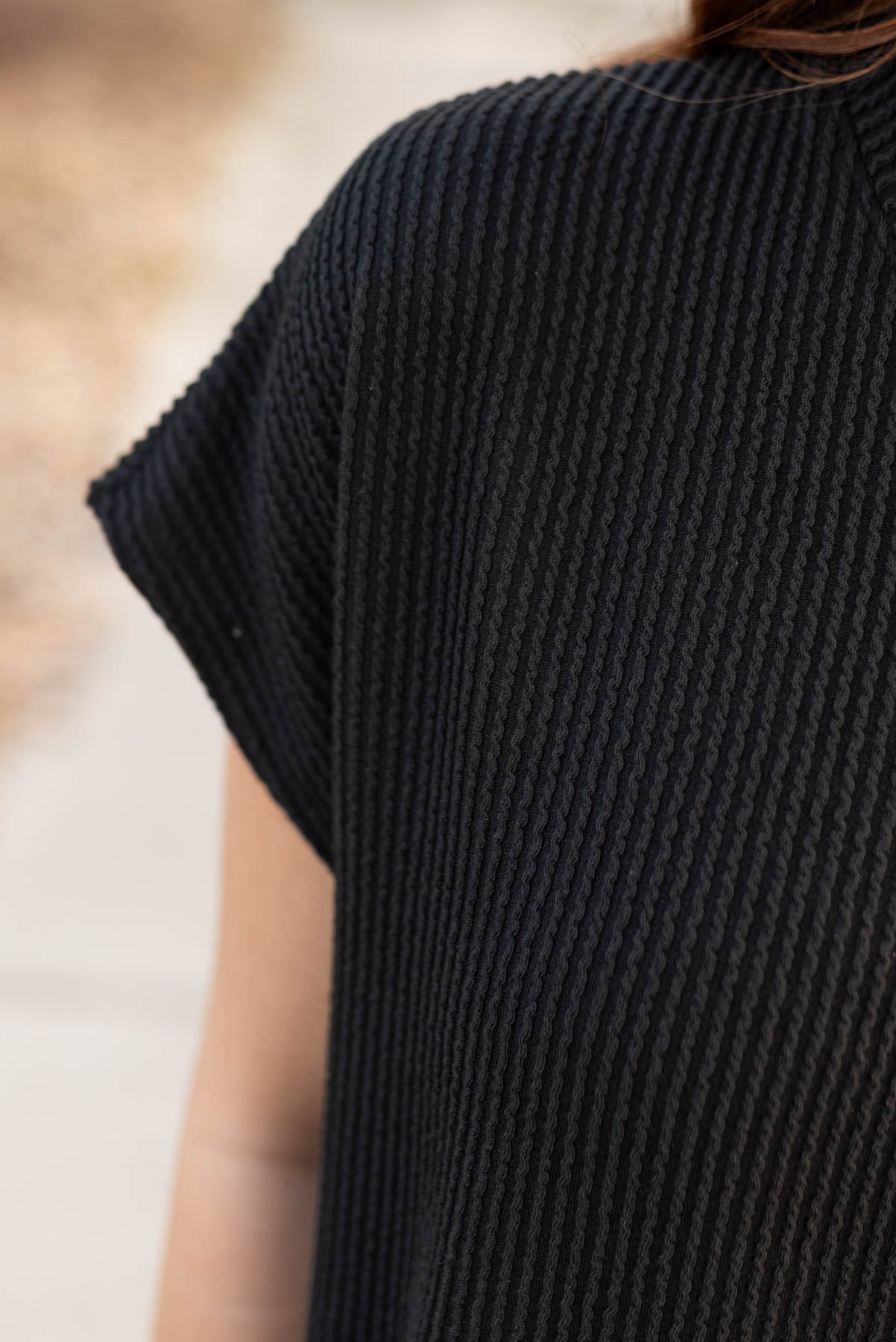 Close up of the fabric and sleeve on the black ribbed top