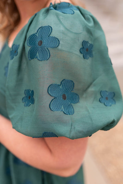 Close up of the fabric on the sleeve of a hunter green floral dress