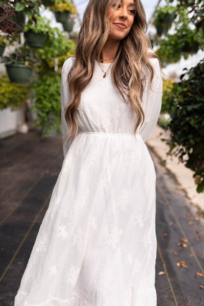 Front view of a small embroidered white dress with long sleeves