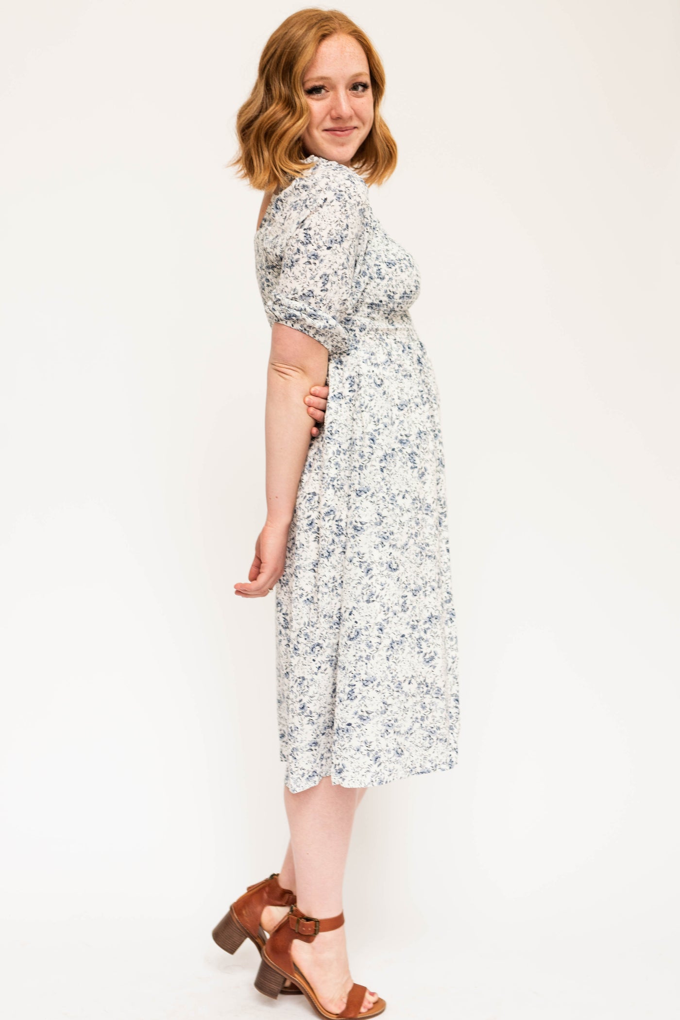 Side view of a blue and white short sleeve floral dress with a smocked bodice.