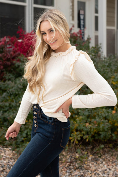 Side view of the cream ruffle long sleeve top