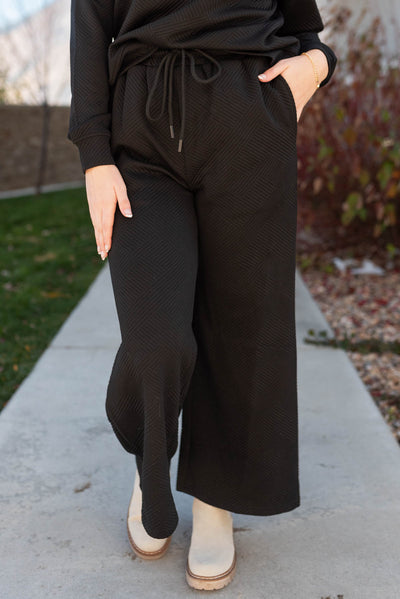 Front view of the wide leg pants on a black textured lounge set
