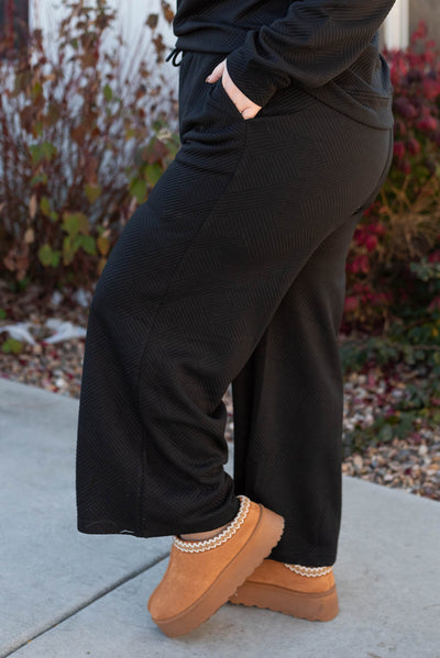Side view of the plus size pants of the black textured lounge set