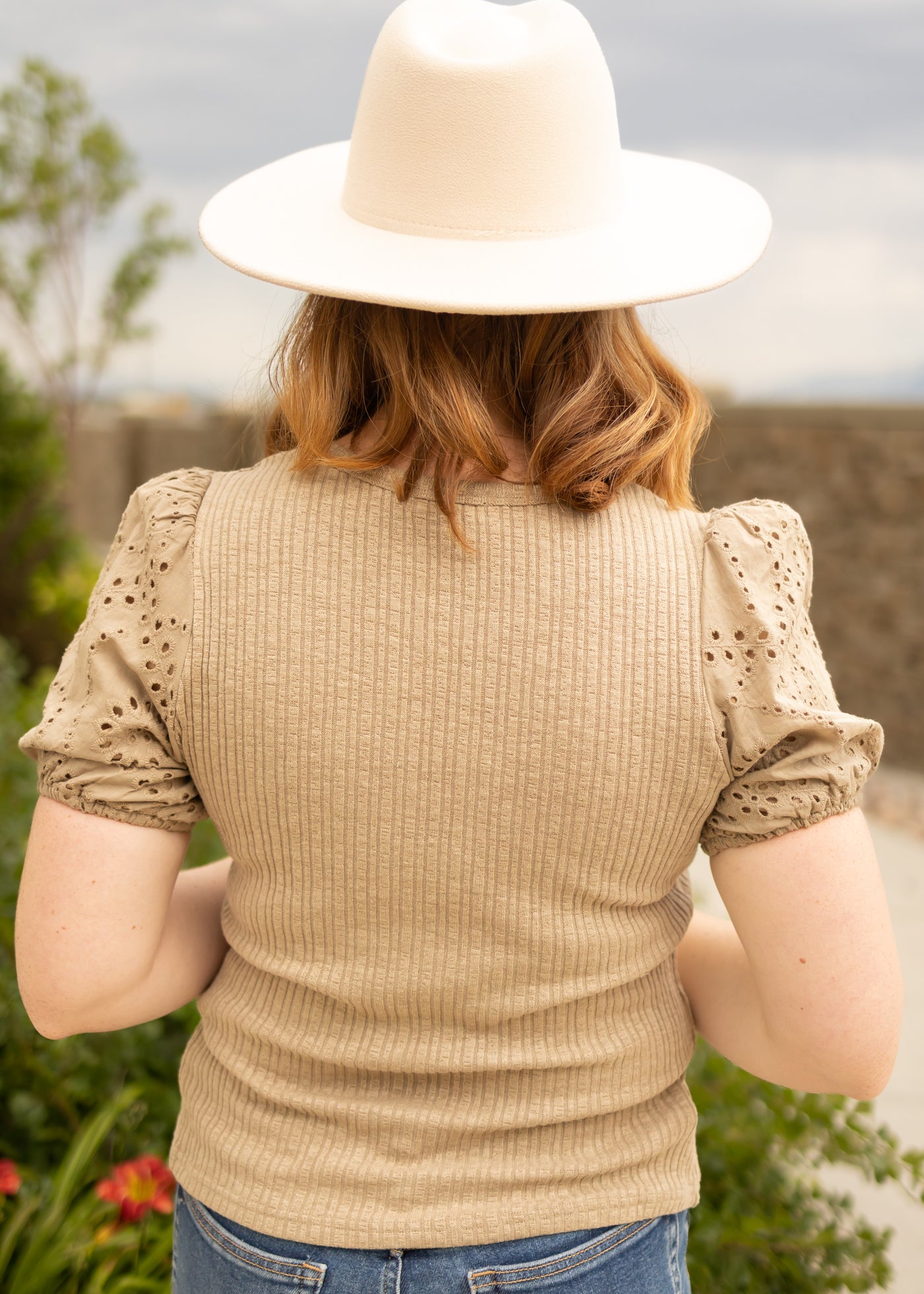 Back view of a taupe top with eyelet fabric sleeves