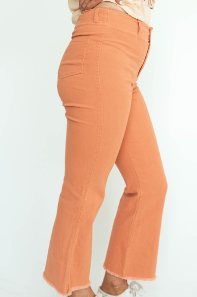 Side view of ginger straight leg, ankle length pants with a frayed edge.