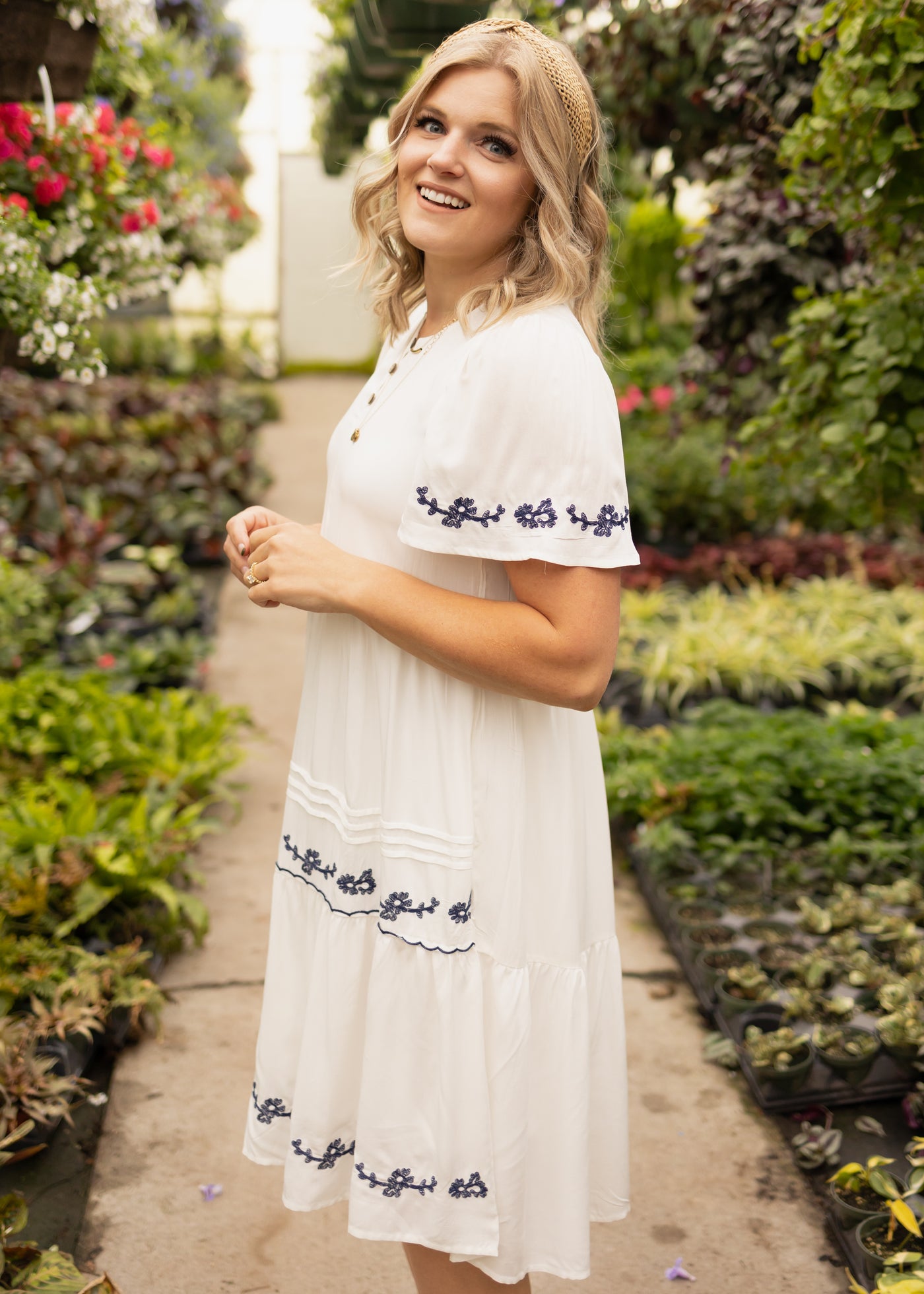Side view of a short sleeve white dress with blue embroidery