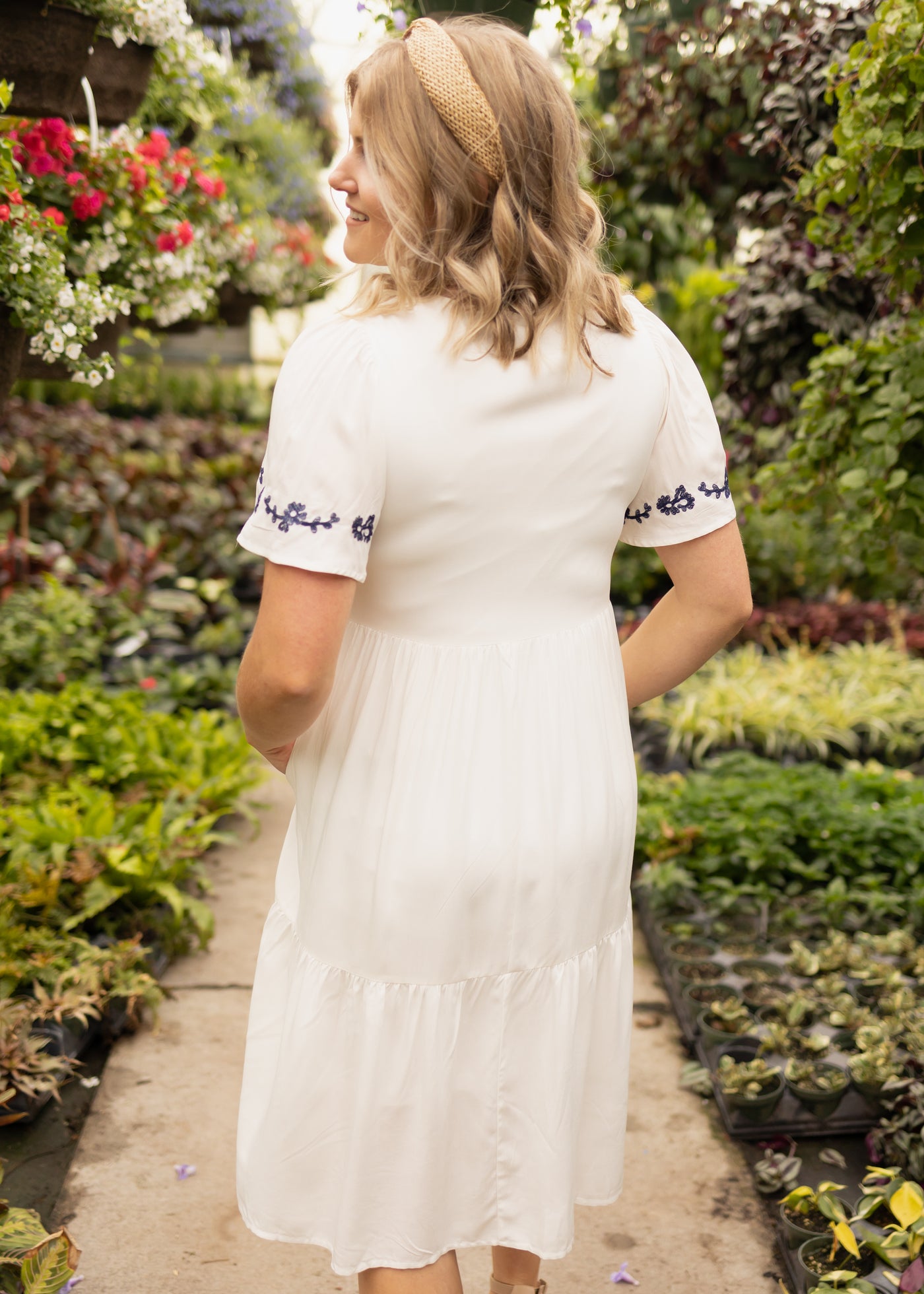 Back view of a short sleeve white dress with embroidery on the sleeves