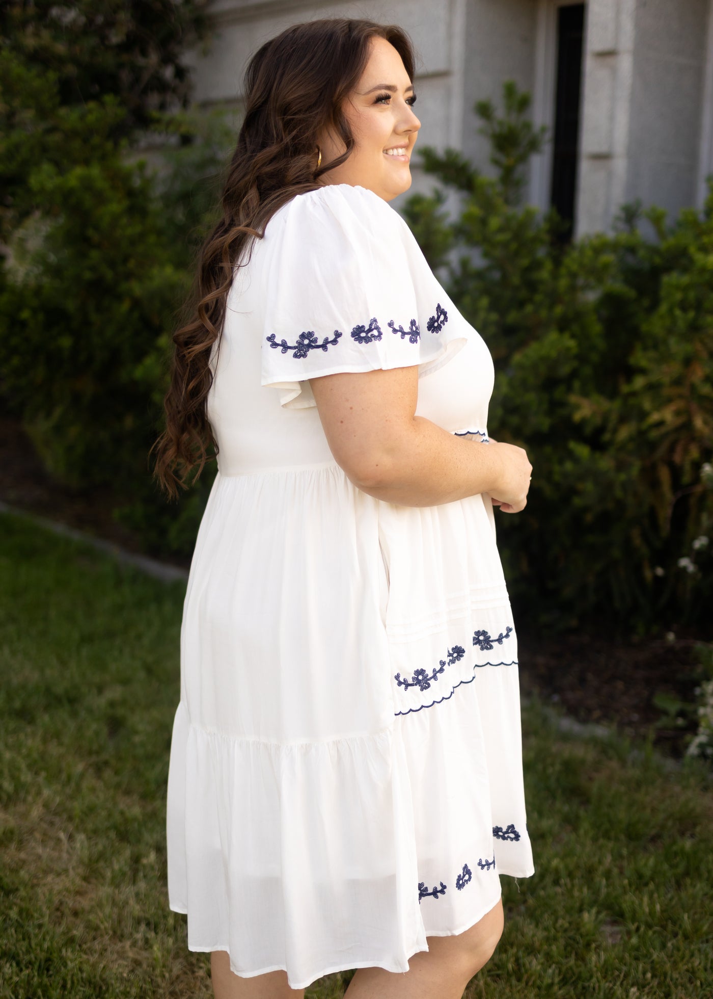 Side view of a plus size white dress with blue embroidery