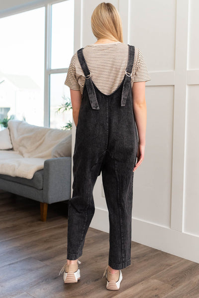 Back view of black denim overalls with buckles in the back