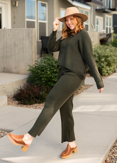 Side view of a dark green sweater and dark green pants that are sold separately 