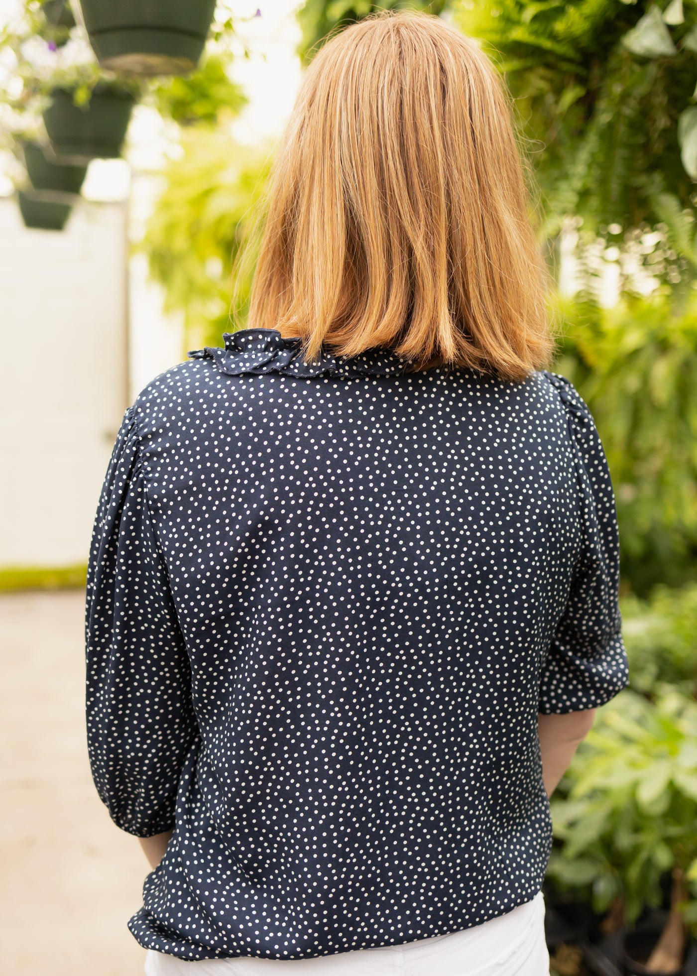 Back view of a navy 3/4 sleeve blouse with little white dots