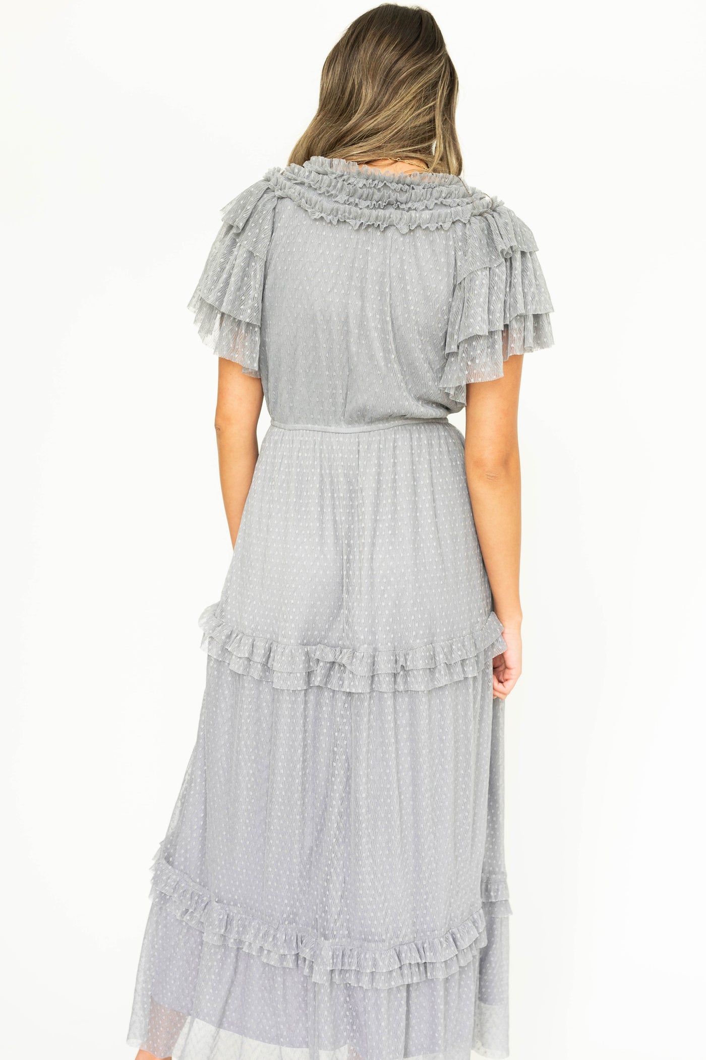 Back view of a blue gray lace short sleeve dress with ruffles on sleeves and neck.