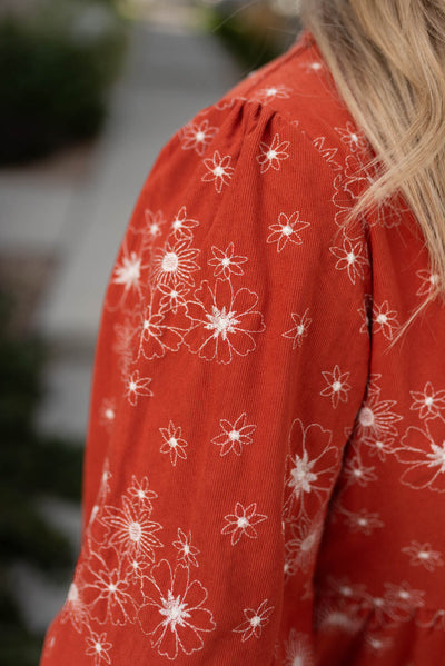 Close up of a rust corduroy embroidered dress