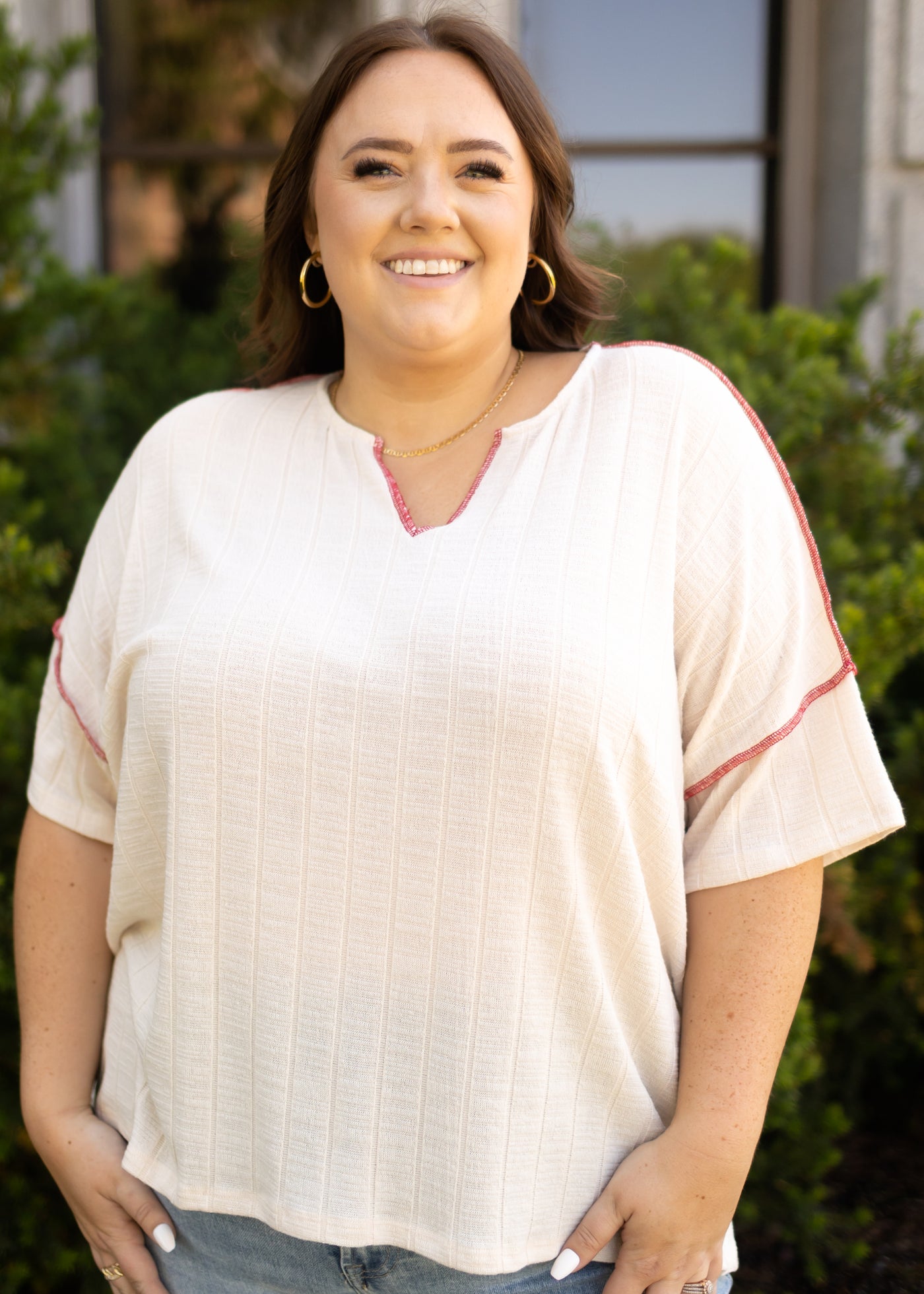 Plus size short sleeve cream top with a v-neck and orange edging
