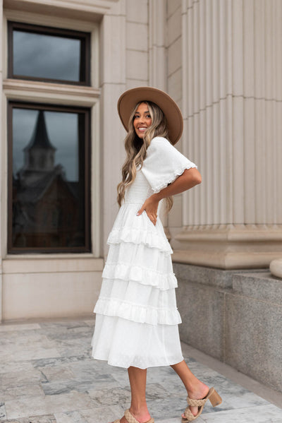 Side view of a white tiered textured dress with short sleeves