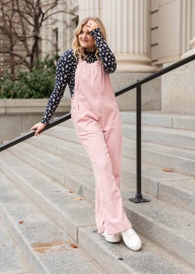 Front view of dusty pink corduroy overalls with straight legs