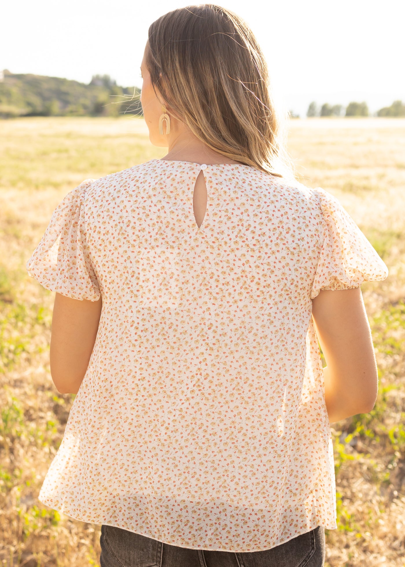 Back view of a short sleeve ivory floral top