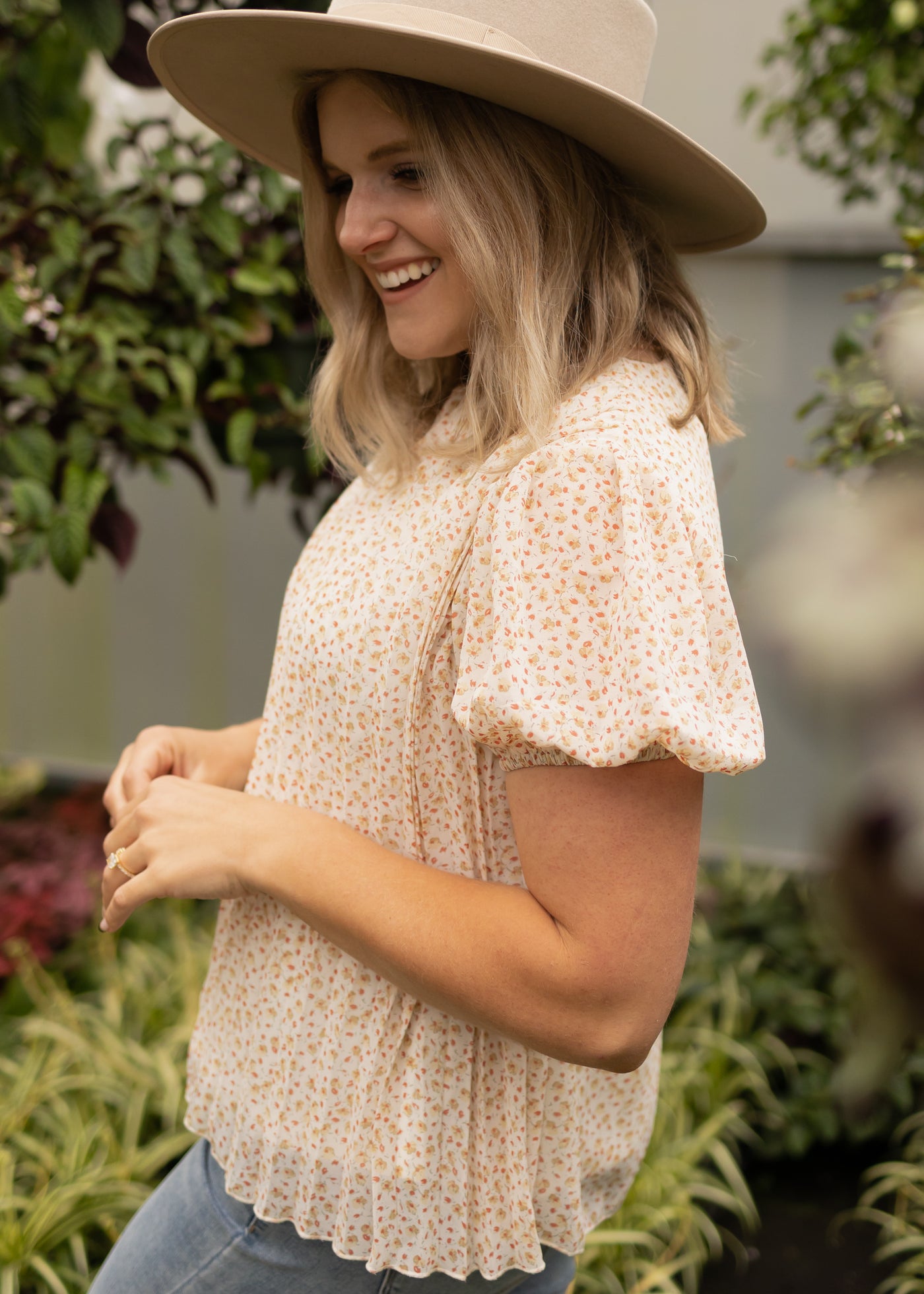 Side view of a short sleeve ivory floral top with sheer fabric