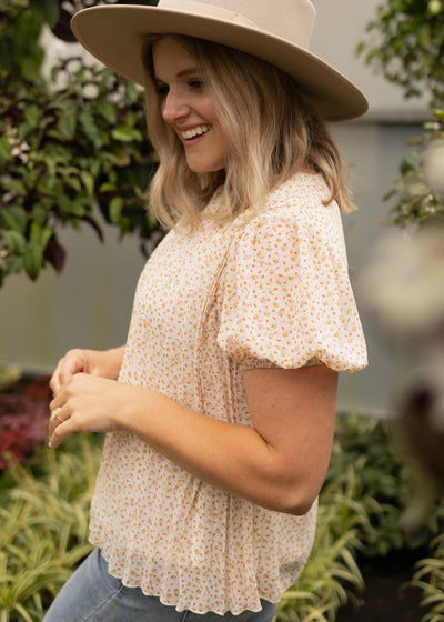 Side view of a short sleeve ivory floral top with sheer fabric