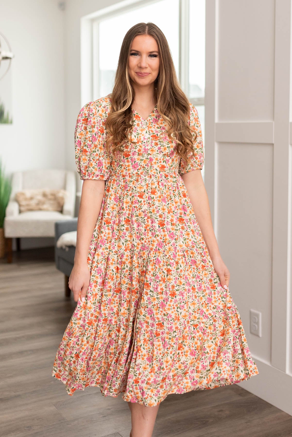 Front view of a small apricot floral dress with short sleeves and that buttons up