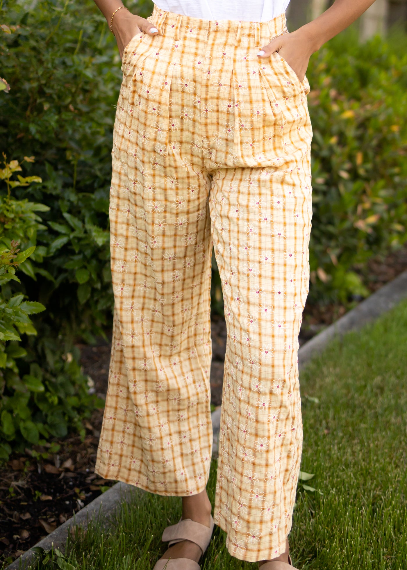 Front view of yellow pants with pockets and daisy pattern