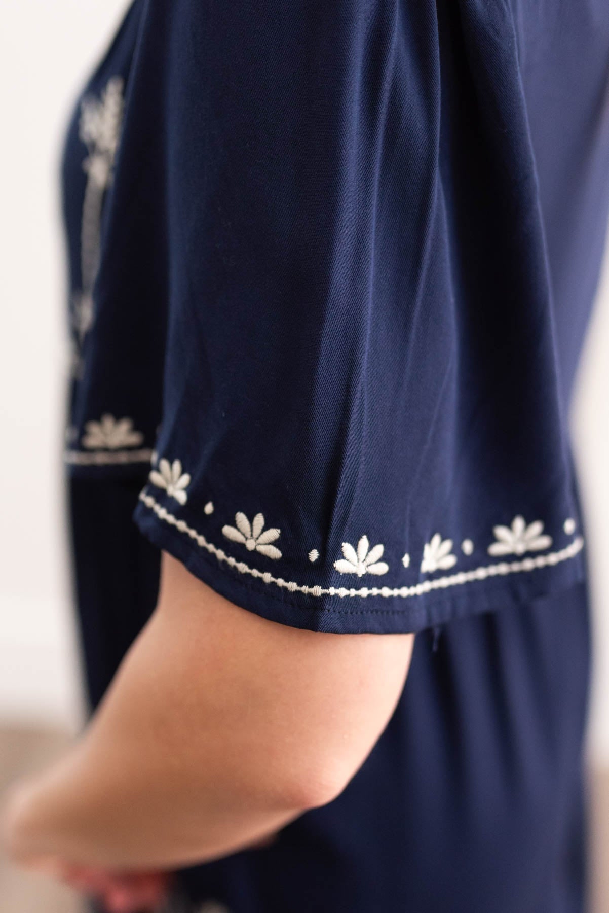Close up of embroidery on a navy embroidered dress