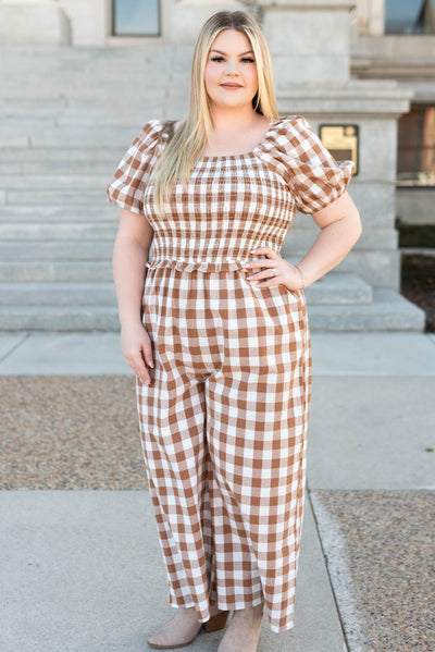 Front view of the taupe gingham jumpsuit with smocked bodice and short sleeves