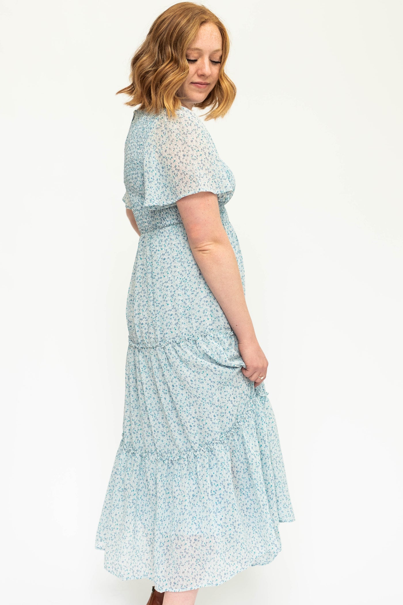 Side view of a blue iris short sleeve floral dress with smocked bodice.