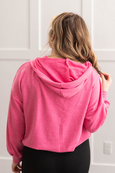 Back view of a hot pink half zip pullover with a hood