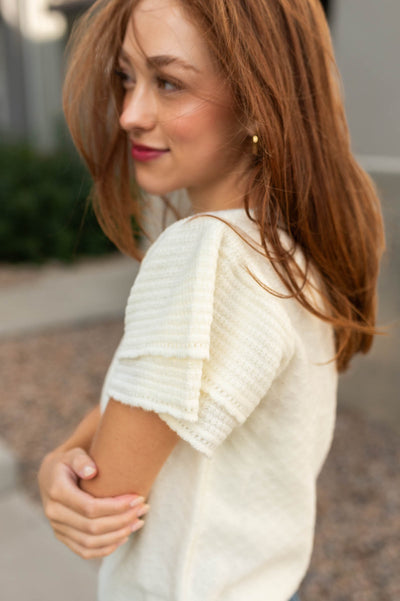 Sleeve of a ivory sweater top