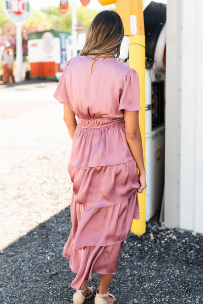 Back view of a mauve ruffle dress with short sleeves and elastic at the waist.