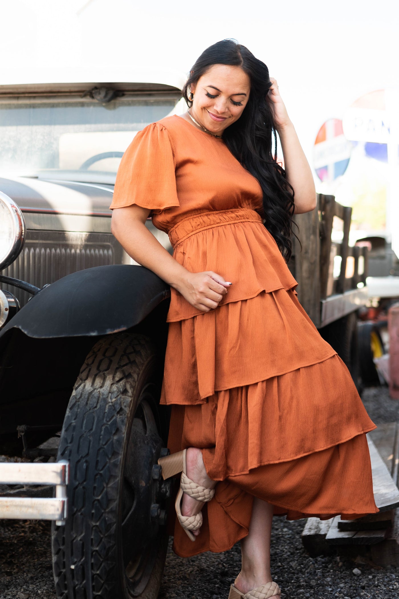  Front view of a short sleeve, satin rust colored ruffle dress with elastic waist