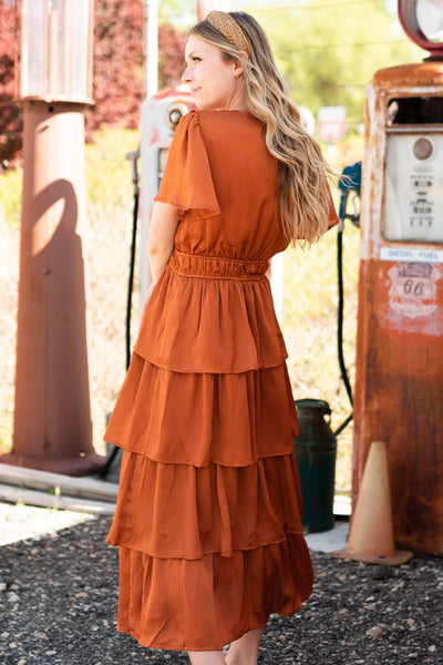 Back view of a rust colored ruffle dress