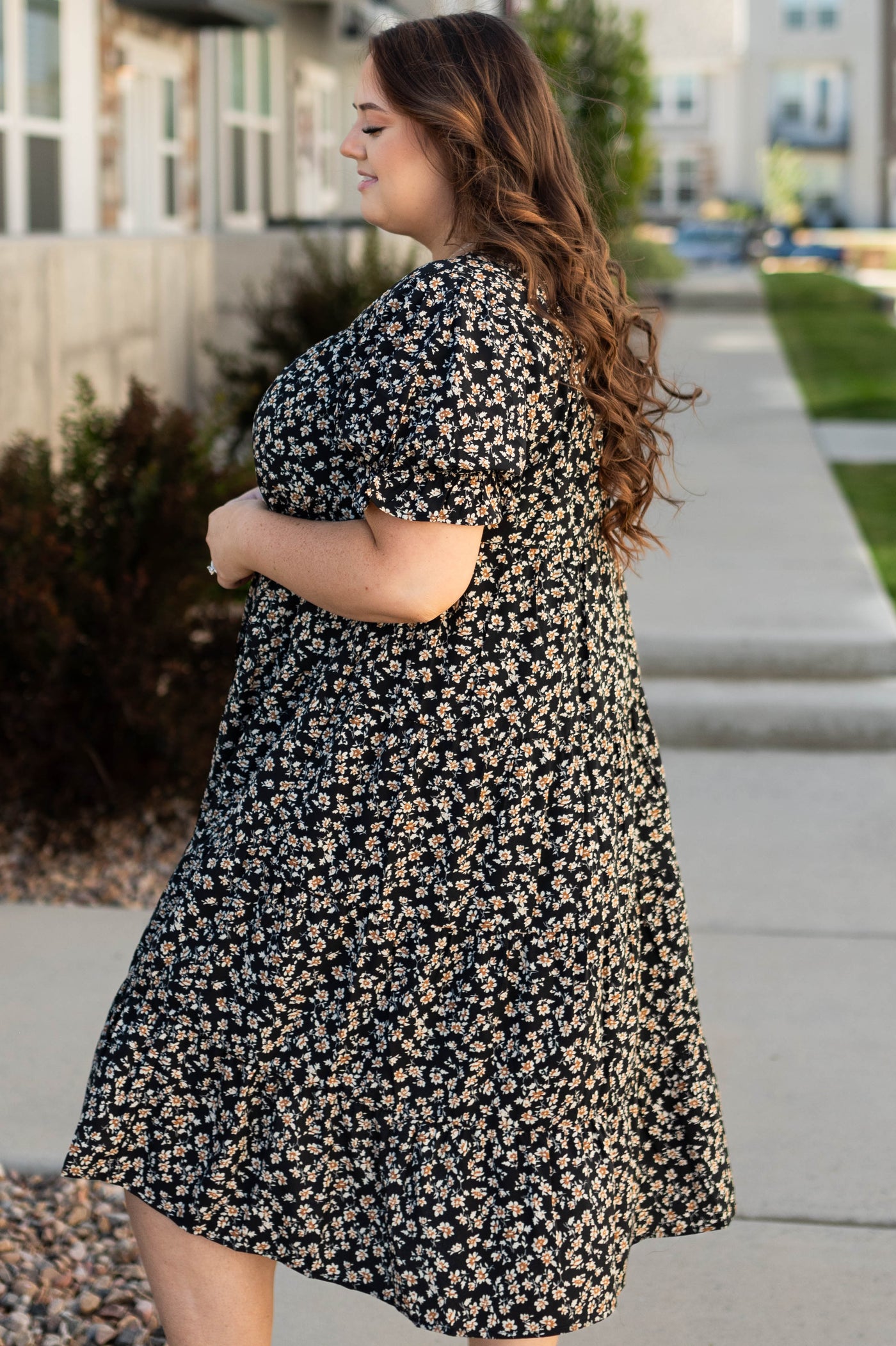 Side view of a plus size black floral dress with short sleeves