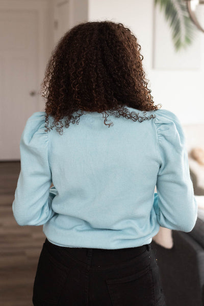 Back view of a sky blue puff sleeve sweater