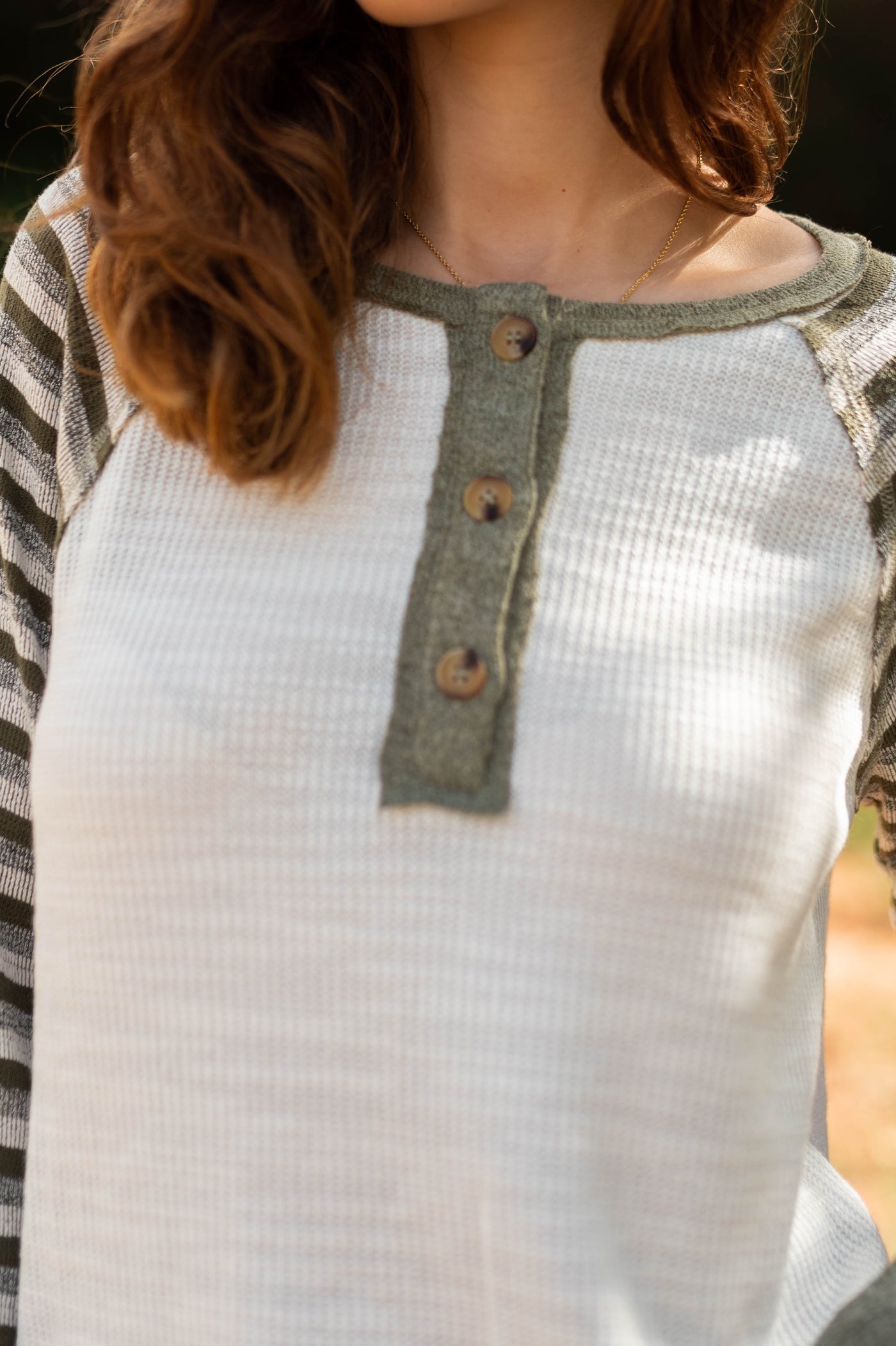 The buttons at the neck of a olive top
